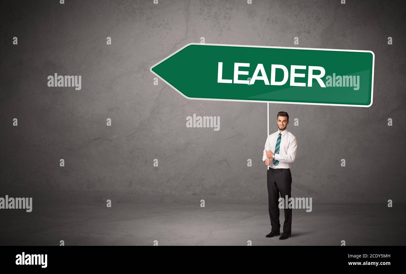 Young business person in casual holding road sign with LEADER inscription, new business direction concept Stock Photo
