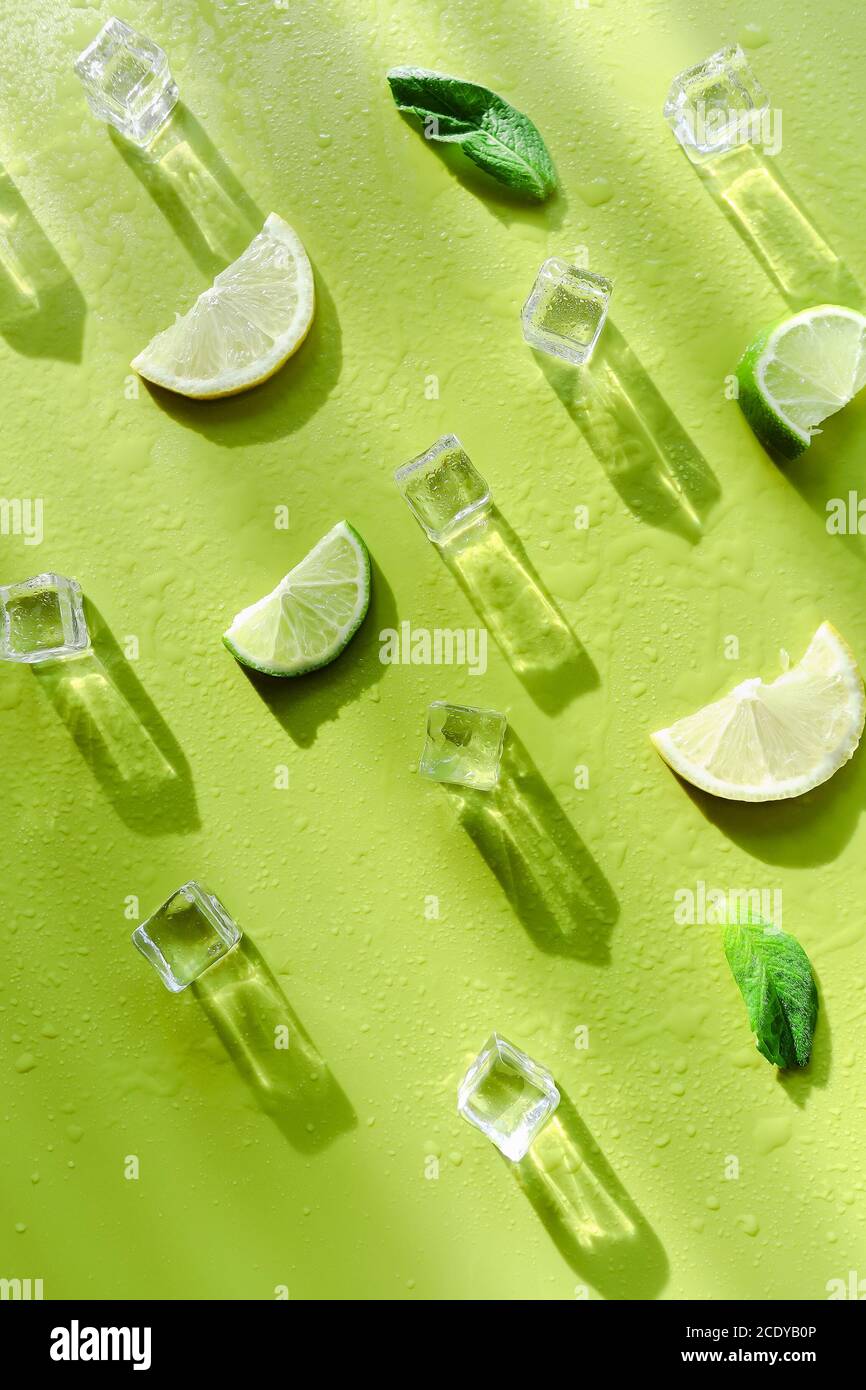 Fresh mint leaf and ice cubes with droplets and lime on green background Stock Photo