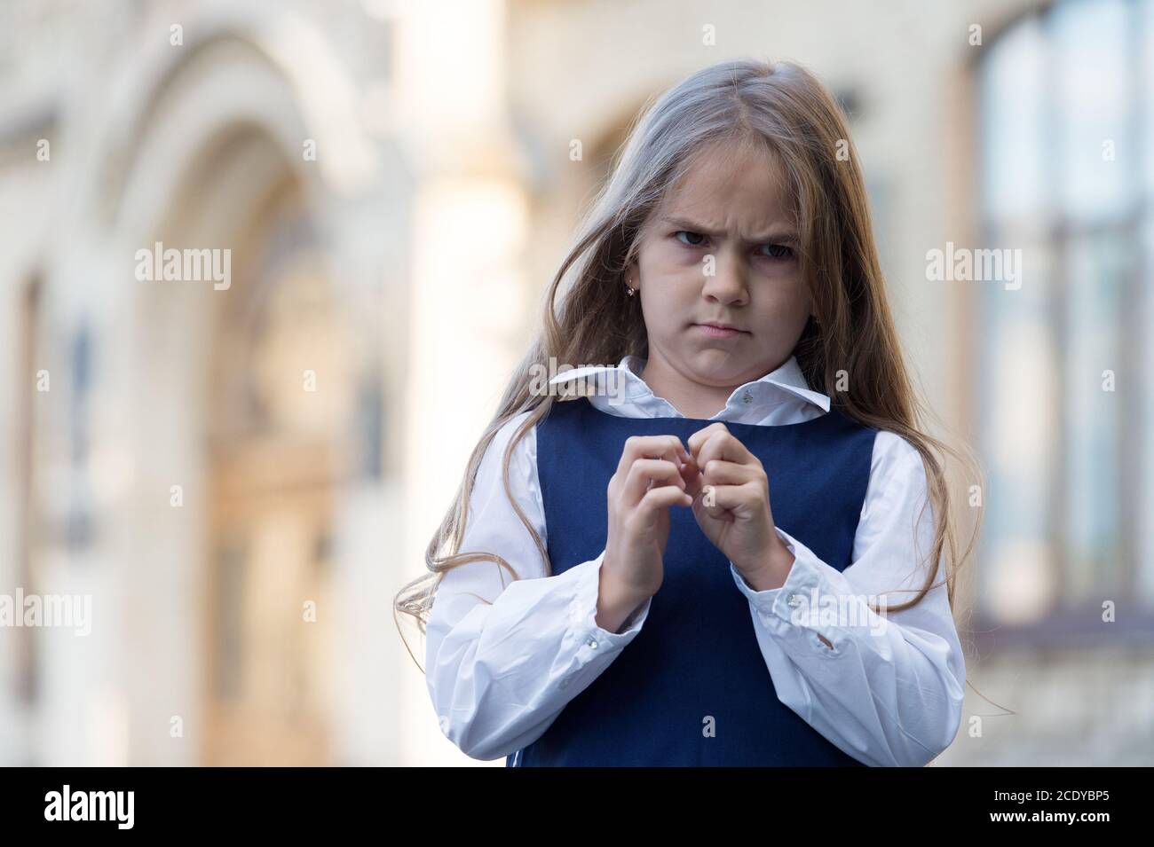 I hate school. Naughty girl child. Unhappy girl back to school. Wearing fashion uniform. Formal education. September 1. Knowledge day. Feeling dread about returning to class, copy space. Stock Photo