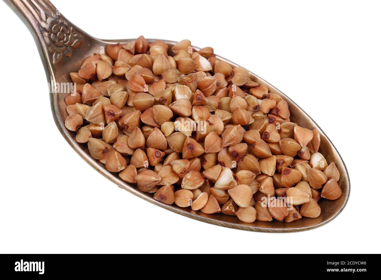 In the old golden spoon there is a small pile of food - buckwheat plant grains  isolated macro Stock Photo