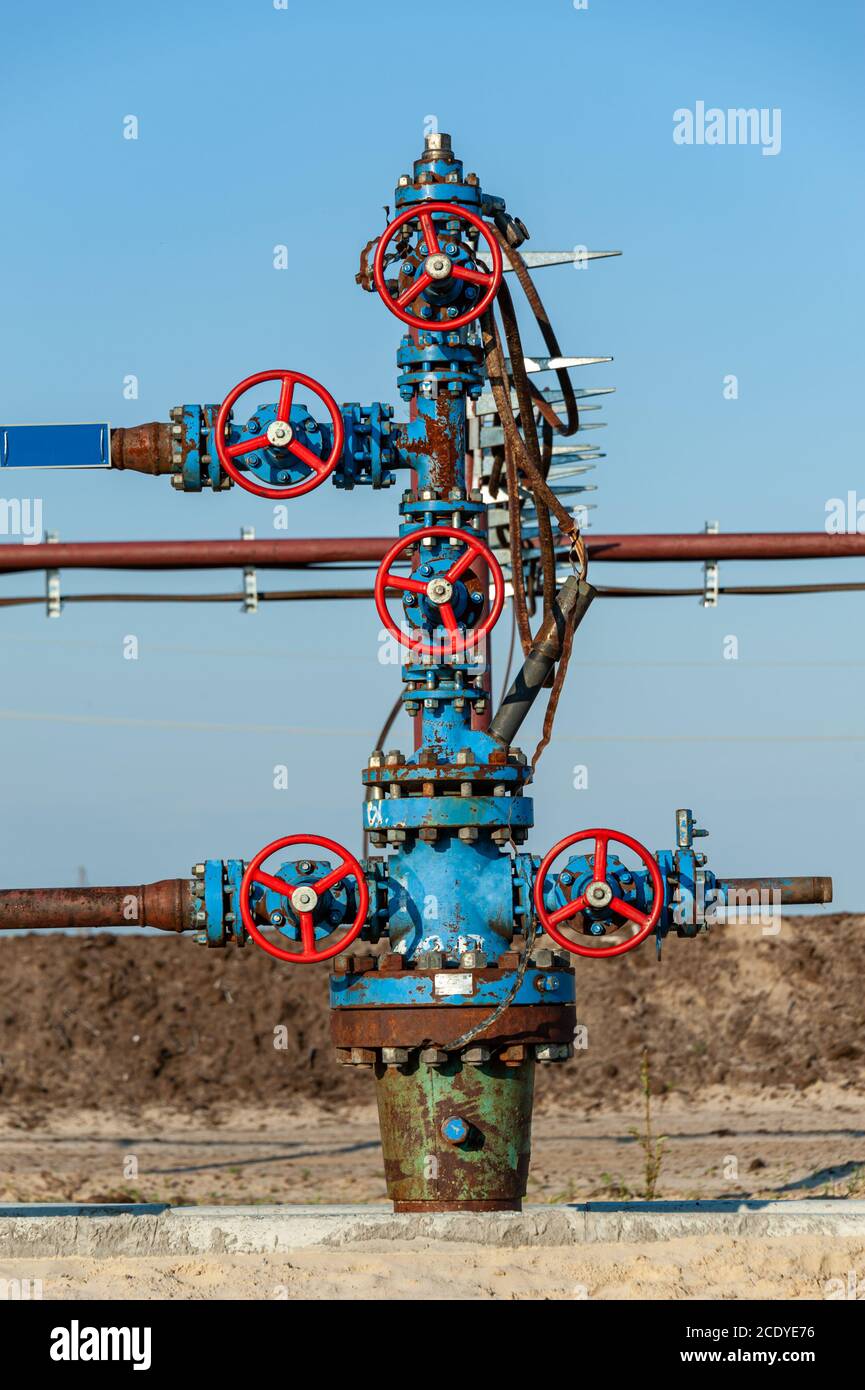Petroleum well wellhead equipment. Hand valve with handwheel on the flow line. Oilfield site. Oil, gas industry concept. Industr Stock Photo
