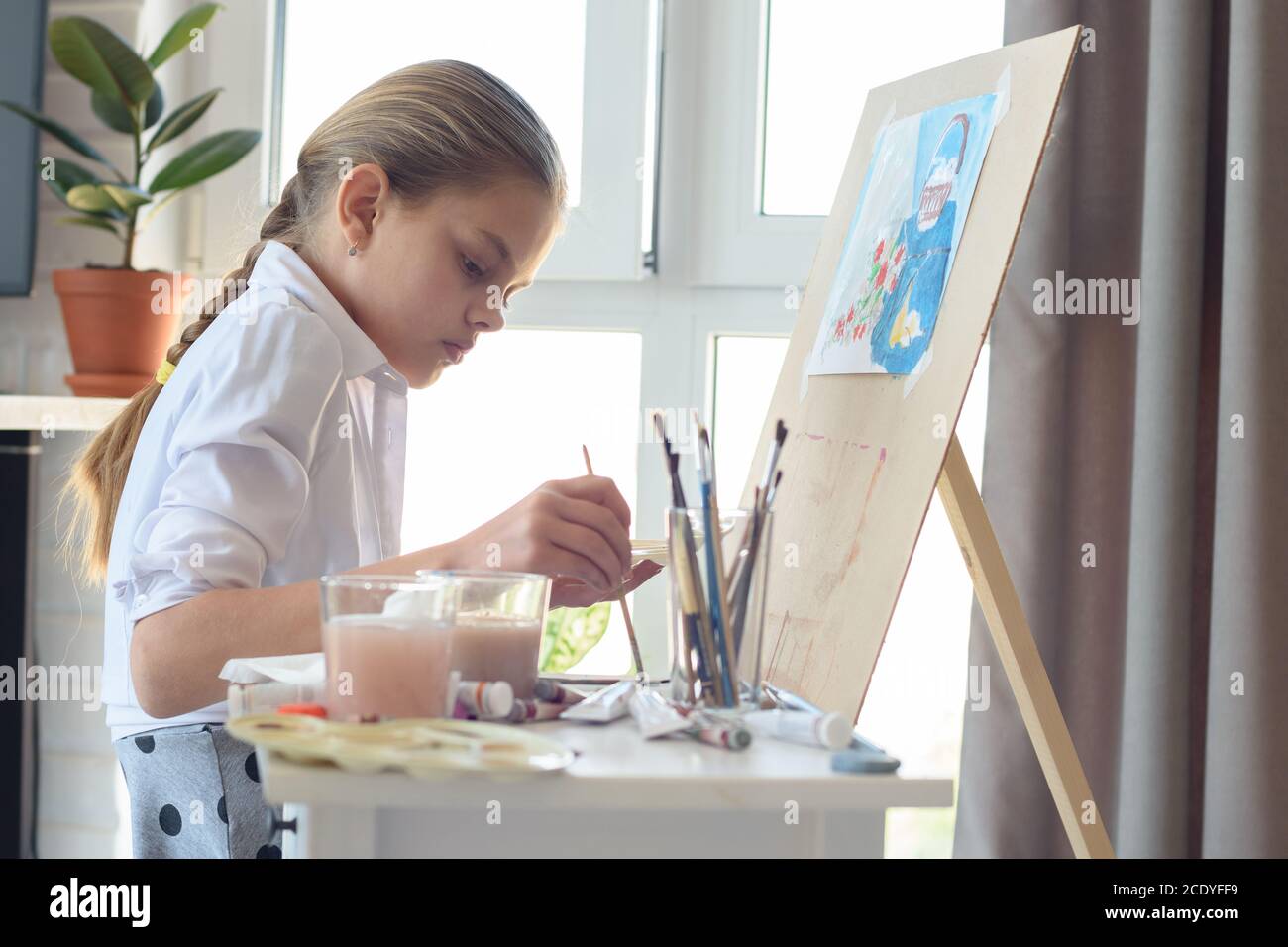 Young artist draws in the studio behind an easel Stock Photo