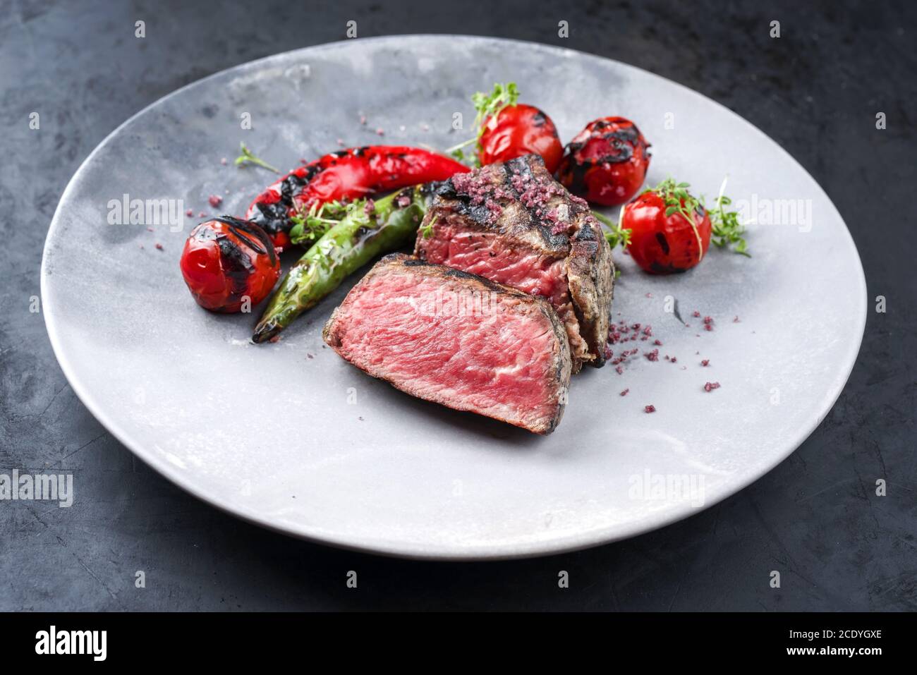 Barbecue dry aged wagyu roast beef steak with tomatoes and chili as closeup on a modern design plate Stock Photo