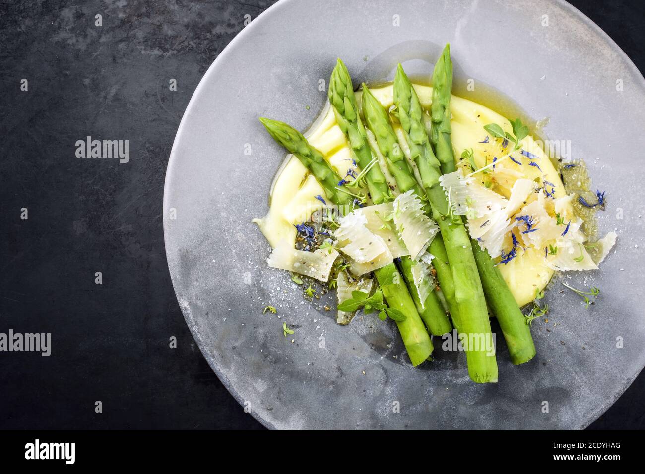 Traditional steamed green asparagus with mashed potato creme and parmesan as top view on a modern design plate with copy space l Stock Photo