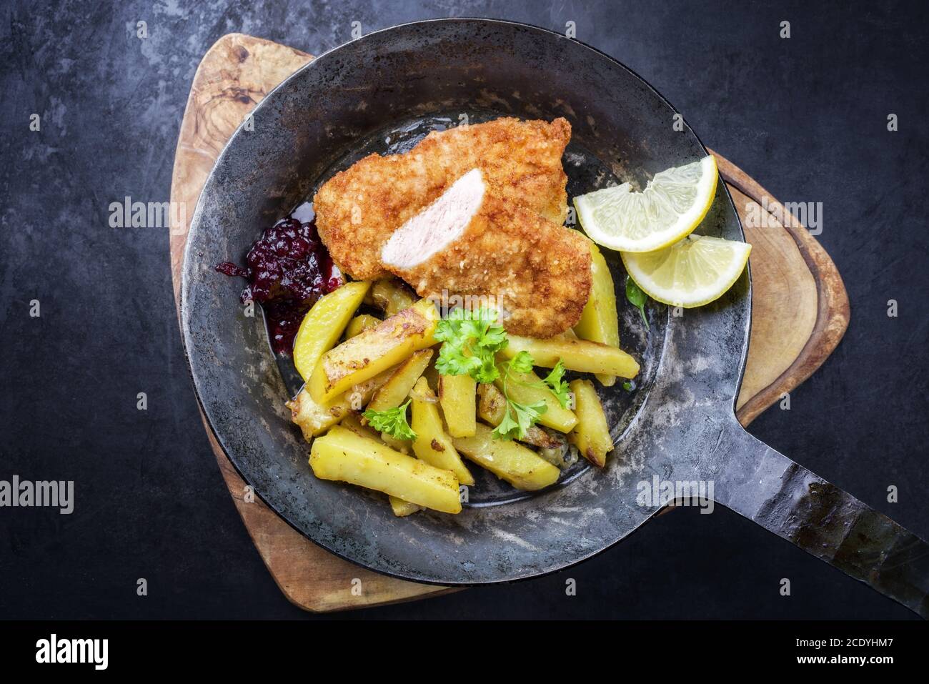 Traditional deep fried veal steak with roast potatoes and cranberry