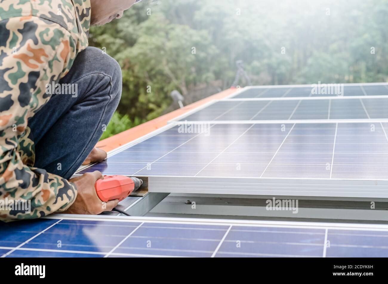 Close up man installing solar panels on a roof house for alternative energy photovoltaic safe energy. power from nature sun power solar cell generator Stock Photo