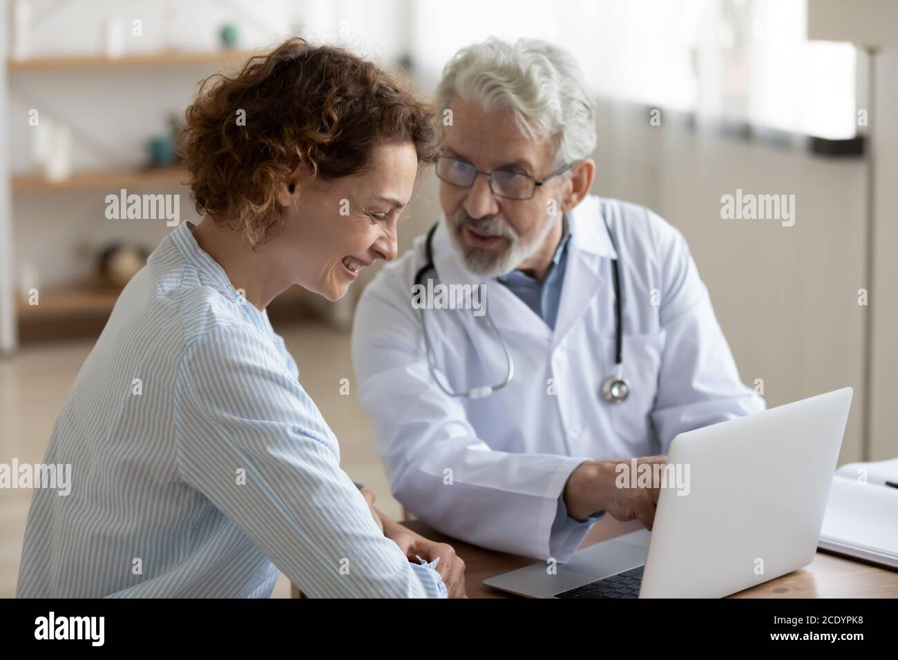 Friendly mature doctor talking to laughing patient at meeting Stock Photo