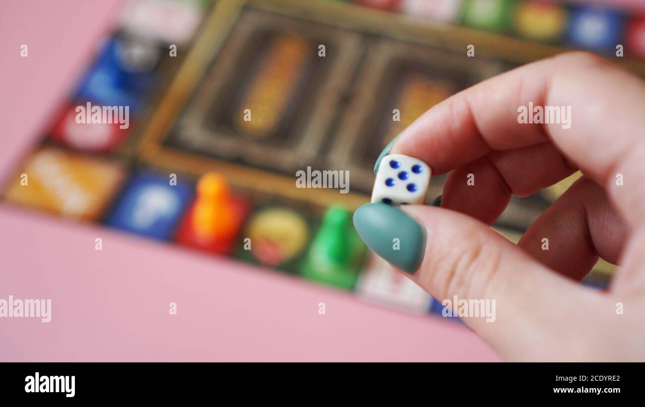 Hand throws the dice on the background of colorful blurred Board games