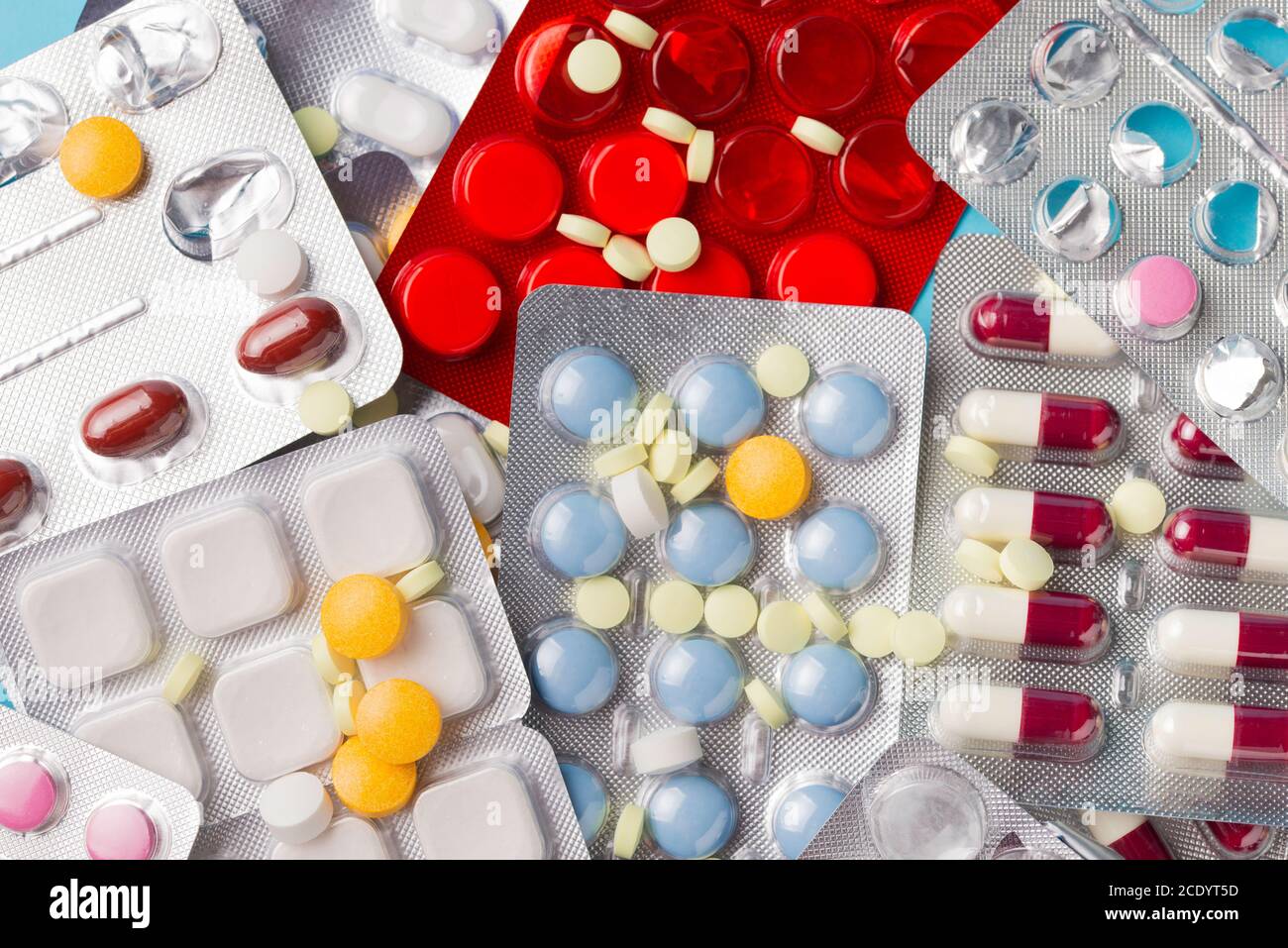 Different tablets, pills in foil blister packs, medications drugs on blue background. Stock Photo