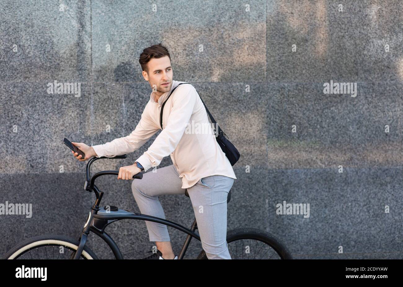 Ecologic transport concept. Serious man with bag rides on bicycle and looks away Stock Photo