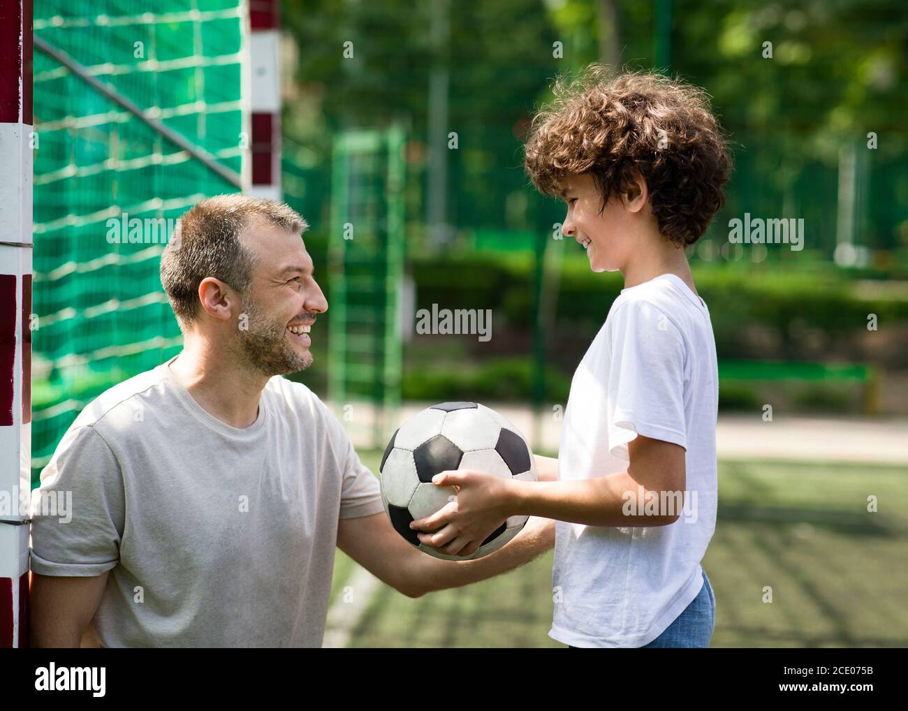 Happy father playing football on a grass with son Stock Photo