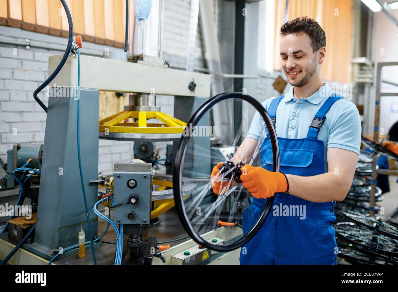 Worker holds bicycle wheel near machine tool Stock Photo Alamy