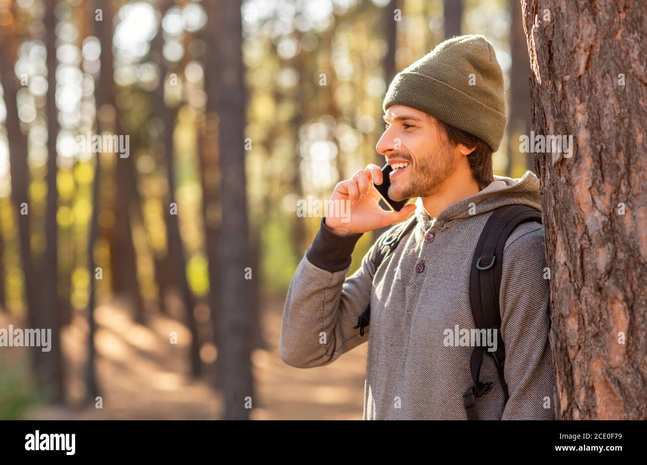 Happy young man backpacker talking on phone while hiking Stock Photo