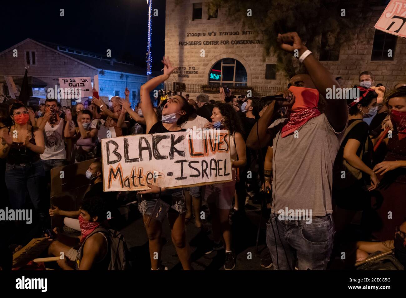 JERUSALEM, ISRAEL - AUGUST 29: A demonstrator holds a sign 'Black Lives Matter - Israel' as a member of the Beta Israel community also known as Ethiopian Jews names the names of Ethiopian Jews who were killed by police in recent years during a mass demonstration attended by over 25000 people as part of ongoing demonstrations against Prime Minister Benjamin Netanyahu over his indictment on corruption charges and handling of the coronavirus pandemic near the Prime Minister's official residence on August 29, 2020 in Jerusalem, Israel. A wave of anti-Netanyahu protests has swept Israel over the su Stock Photo