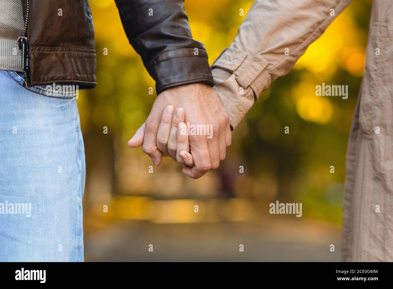 Close up of couple in love holding hands while walking Stock Photo - Alamy