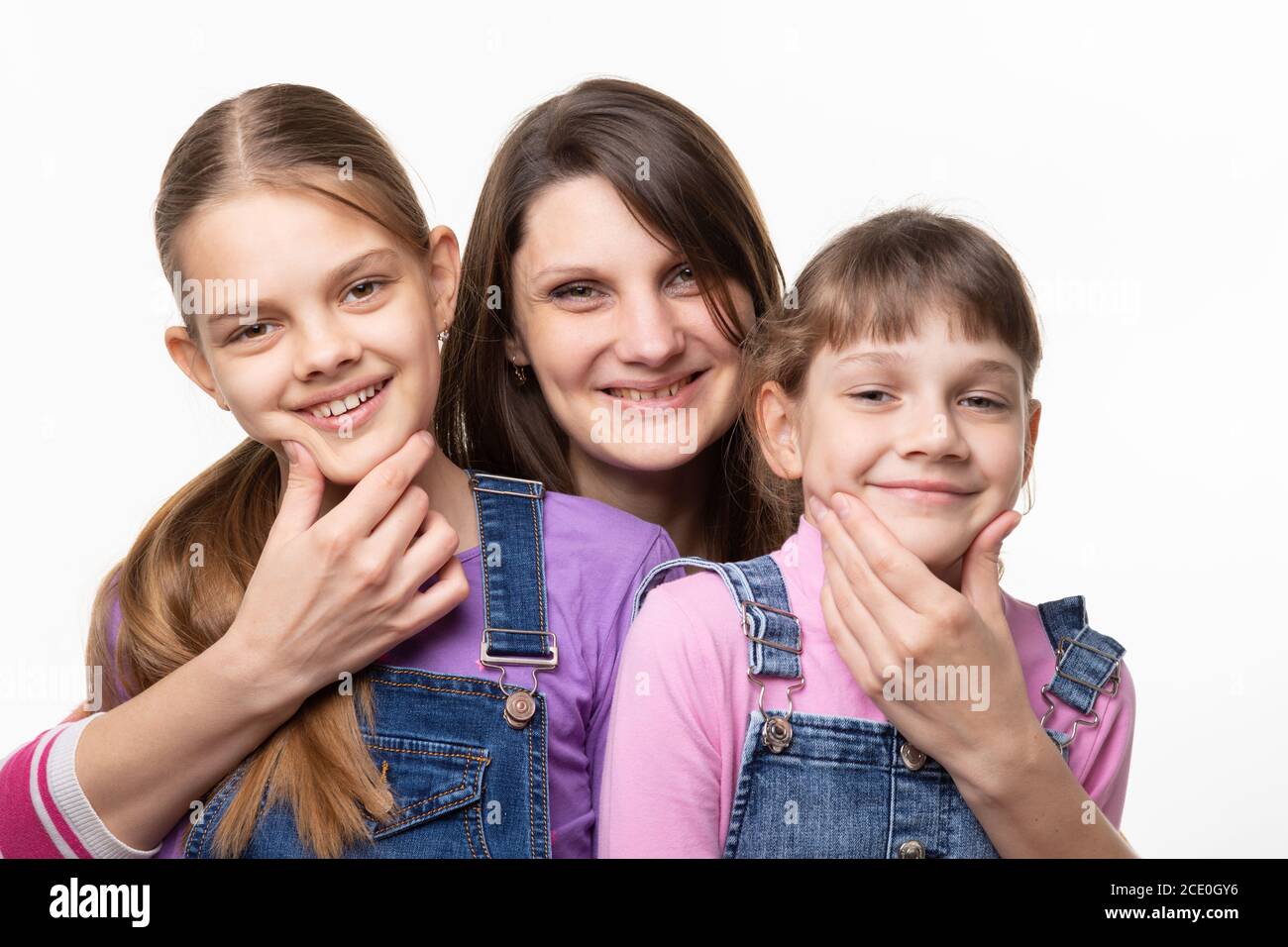 Mom cheerfully holds the children by the chin and looks in the frame Stock Photo