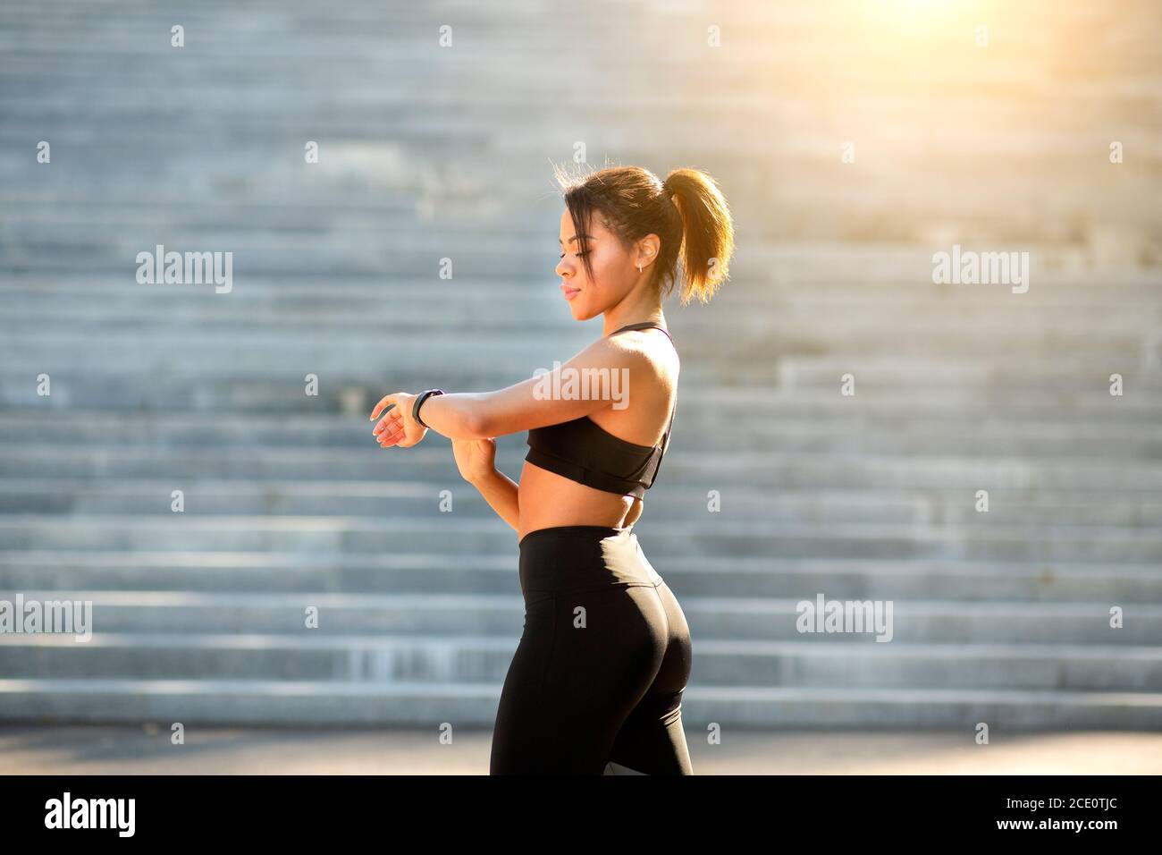 Black sporty woman looking at fitness bracelet during exercising Stock Photo