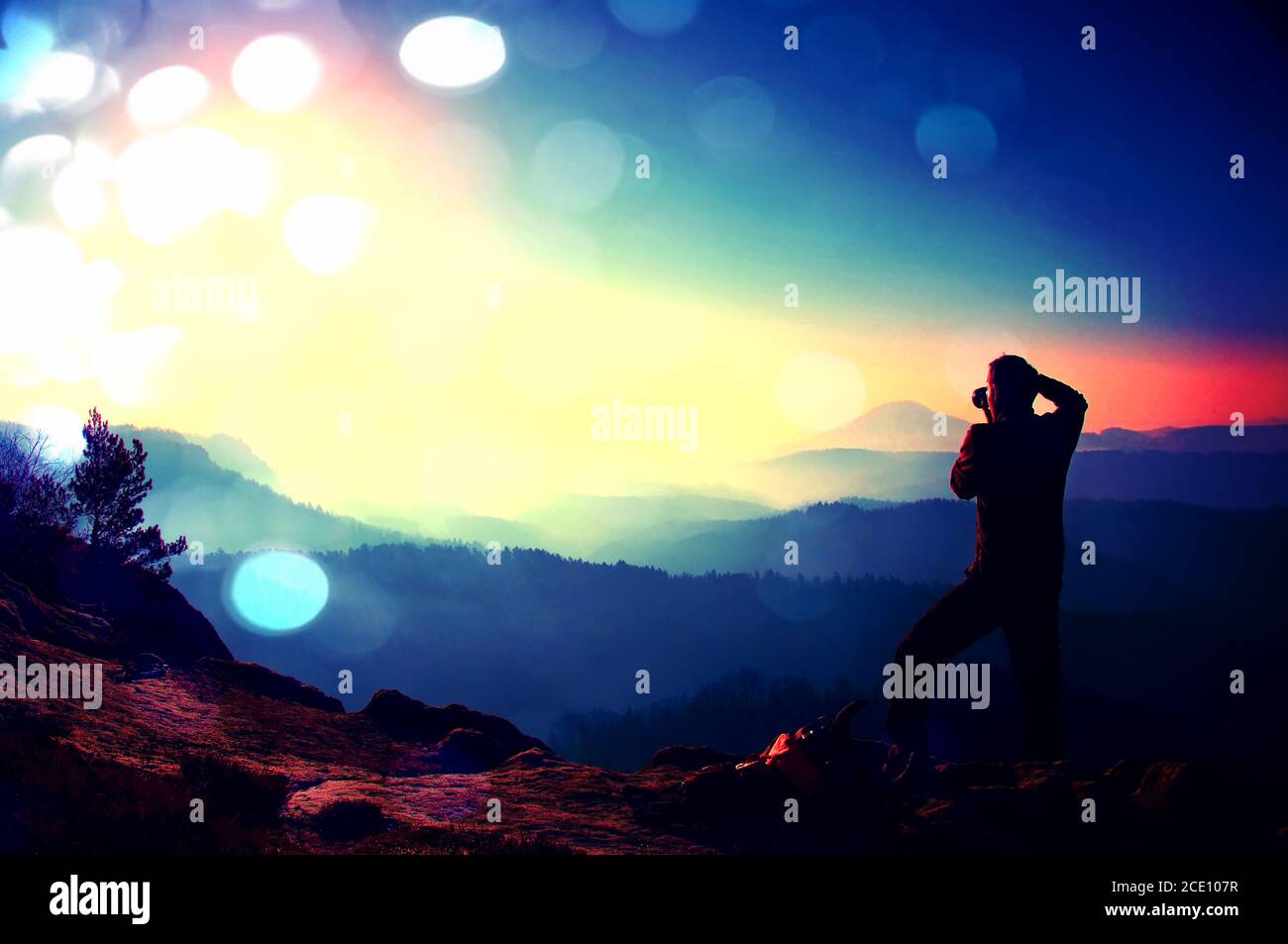 Film grain. Professional photographer takes photos with mirror camera on peak of rock. Dreamy fog Stock Photo
