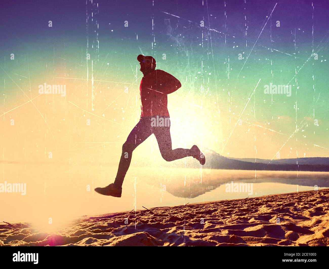 Film effect. Sportsman  running at amazing summer sunset along coastline in sport and healthy lifestyle concept Stock Photo