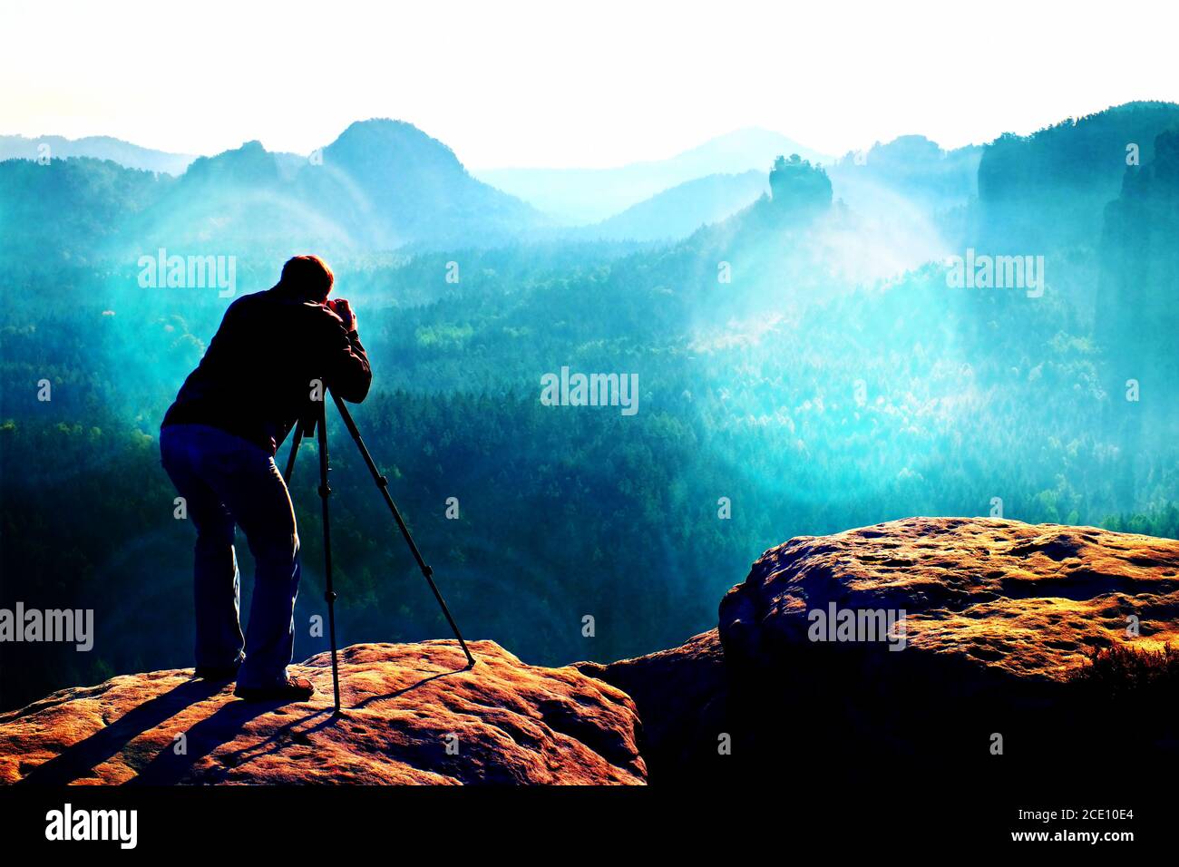 Film grain. Professional on cliff. Nature photographer takes photos with mirror camera on mountaiin peak Stock Photo