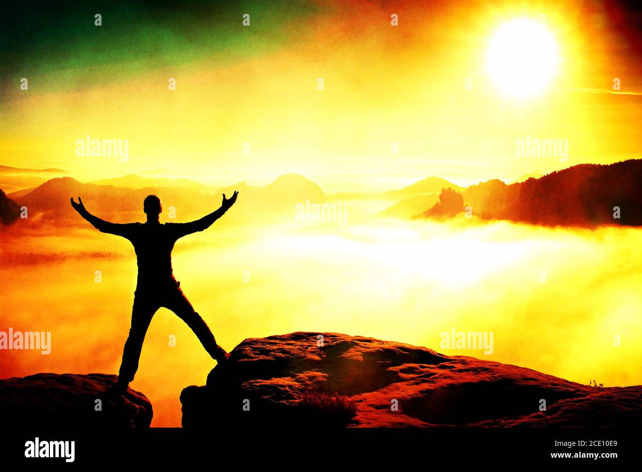 Film grain. Jumping hiker in black celebrate triumph between two rocky peaks. Wonderful daybreak. Stock Photo