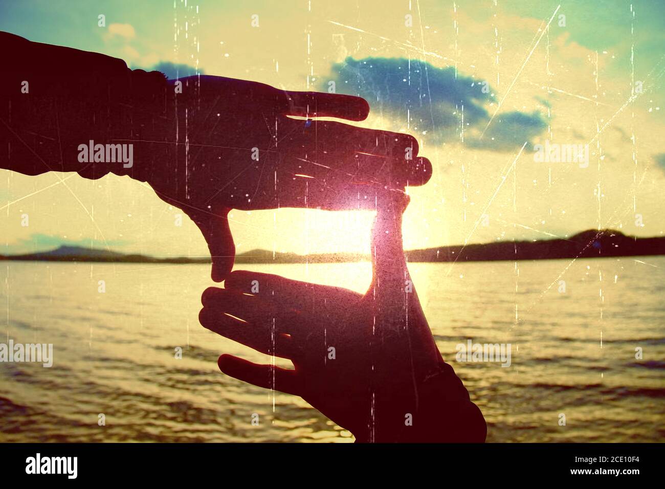 Film grain. Holding hands in square frame with sunset immersing at the horizon. Autumn evening at the lake. Stock Photo