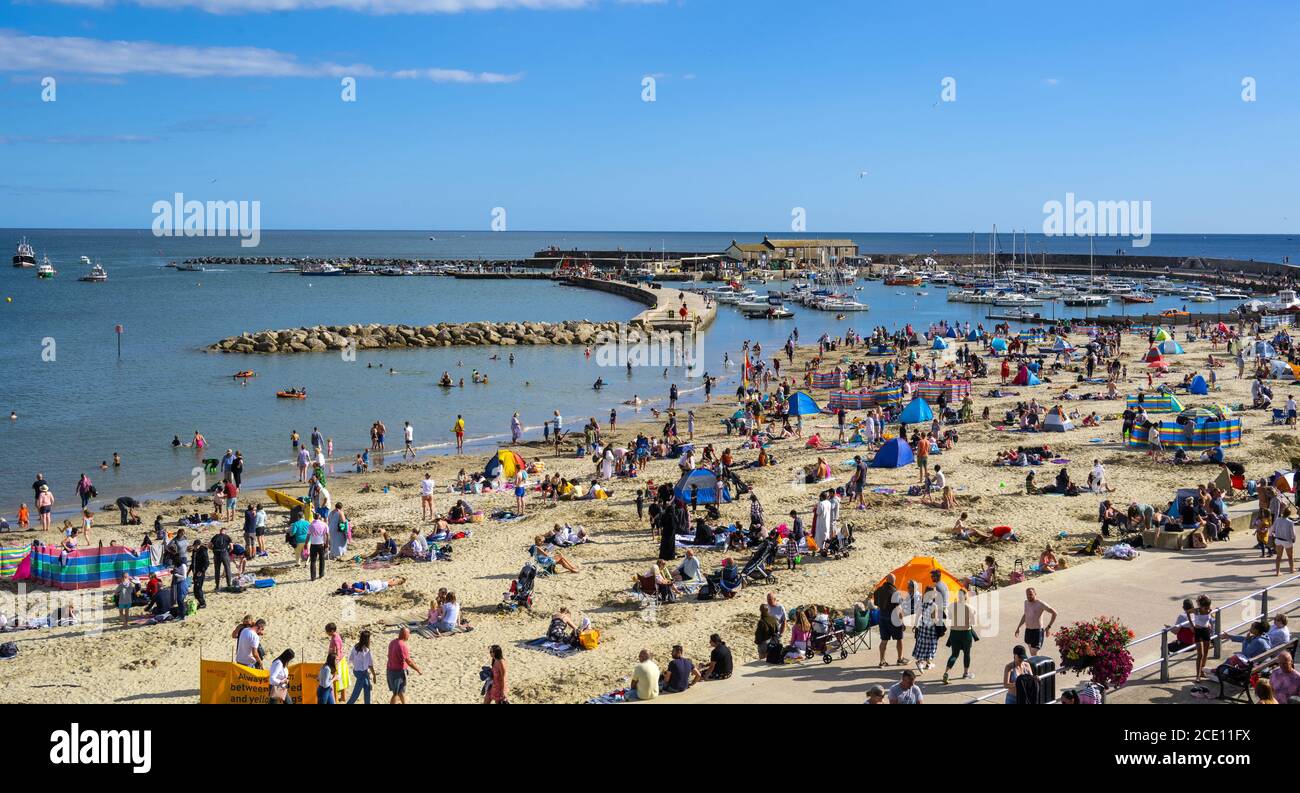 Lyme Regis, Dorset, UK. 30th Aug, 2020. UK Weather: Beachgoers and families flock to the packed beach at the seaside resort of Lyme Regis on Bank Holiday Sunday to soak up the last of the hot sunshine. Credit: Celia McMahon/Alamy Live News Stock Photo