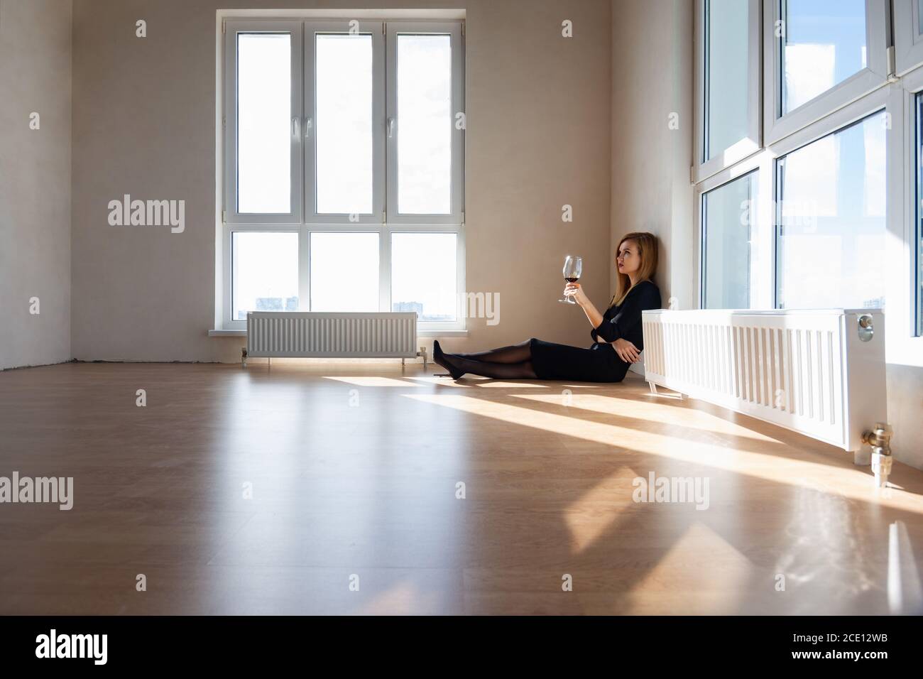 Beautiful elegant girl sits on the floor in a large light room with stained glass windows Stock Photo