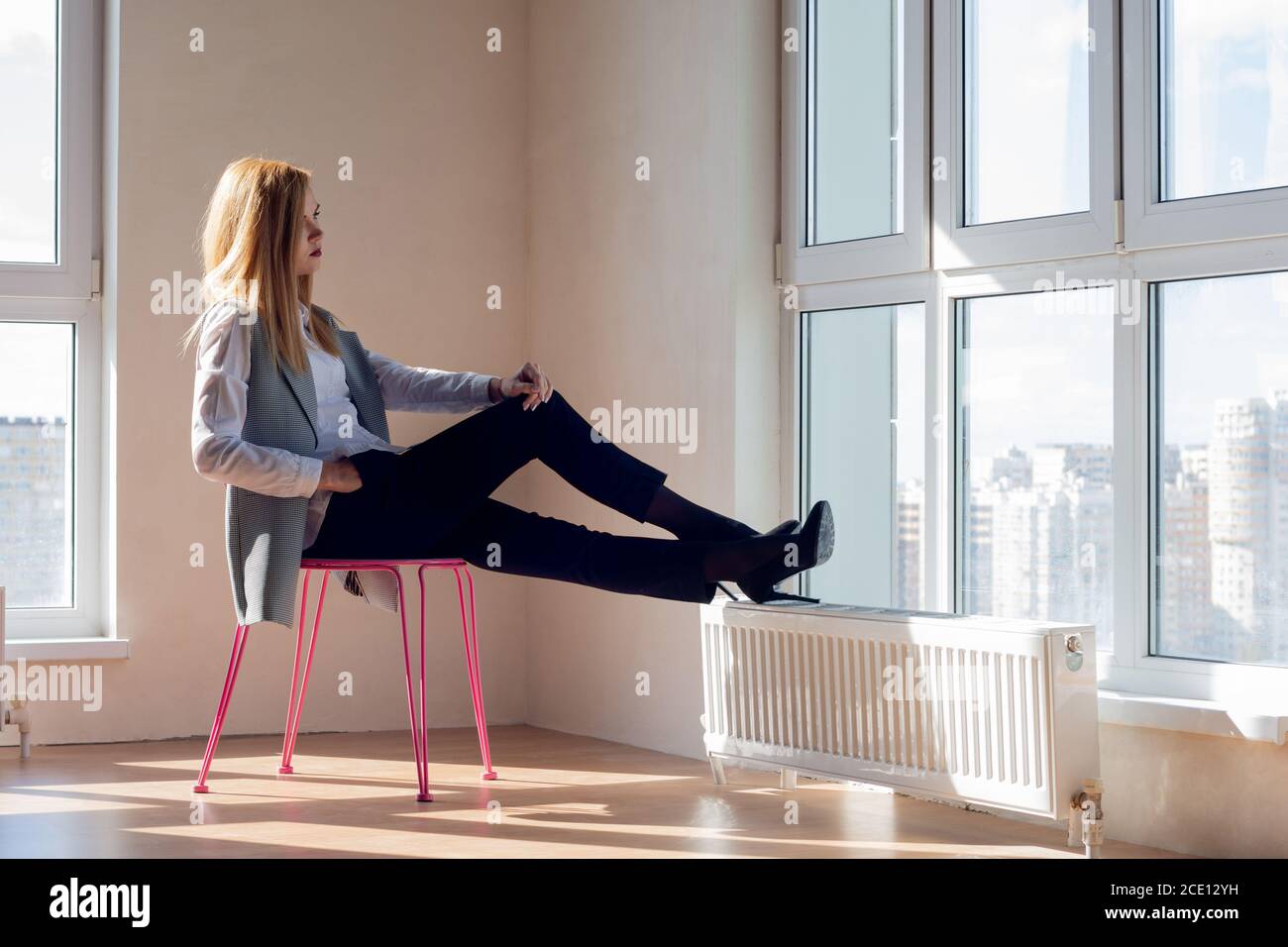 empty room with a girl sitting on a chair in front of the window Stock Photo