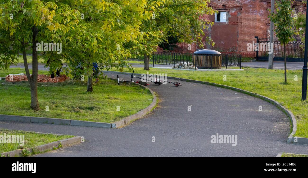 Children's scooters lie on the asphalt in the city Park Stock Photo