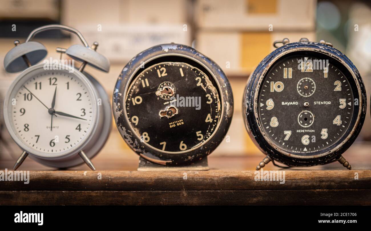 Three Vintage alarm clocks on  a wooden shelf close up front image,   Two black without hands and one white Stock Photo