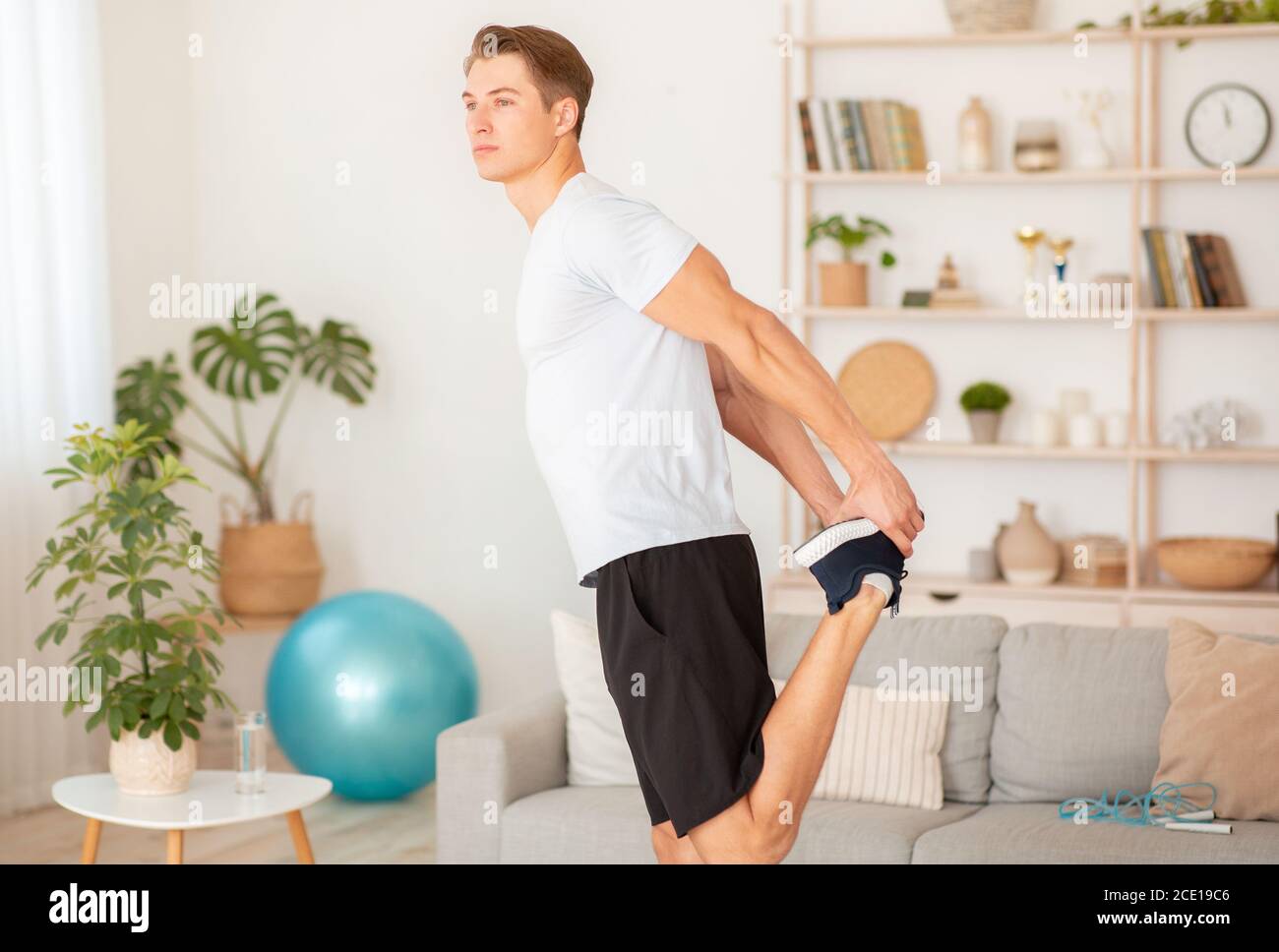 Morning workout for health lifestyle. Muscular guy doing warm-up in interior Stock Photo