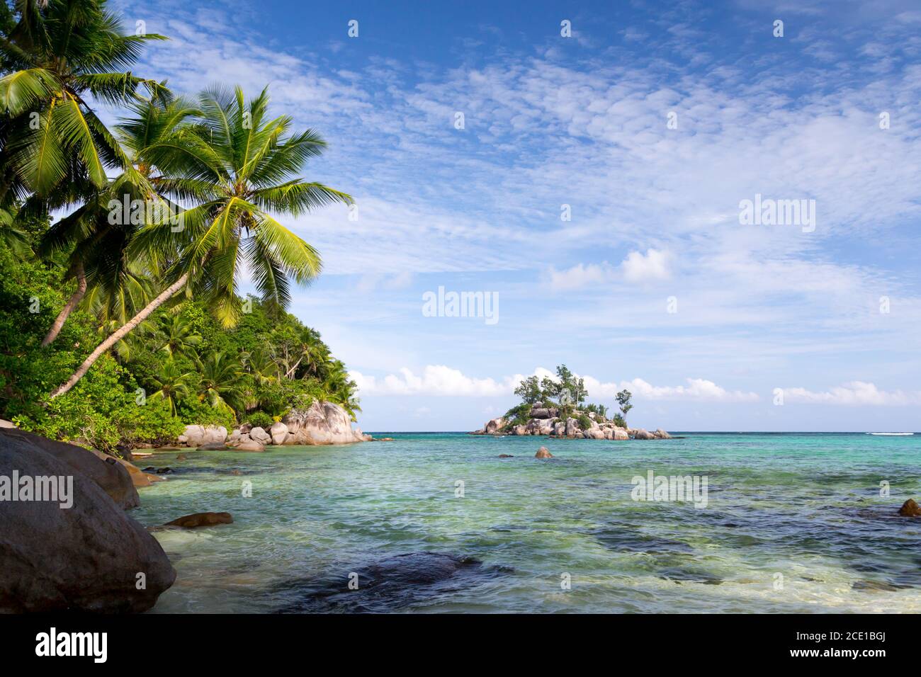 Beach with blue water and blue sky and some rocks Stock Photo - Alamy