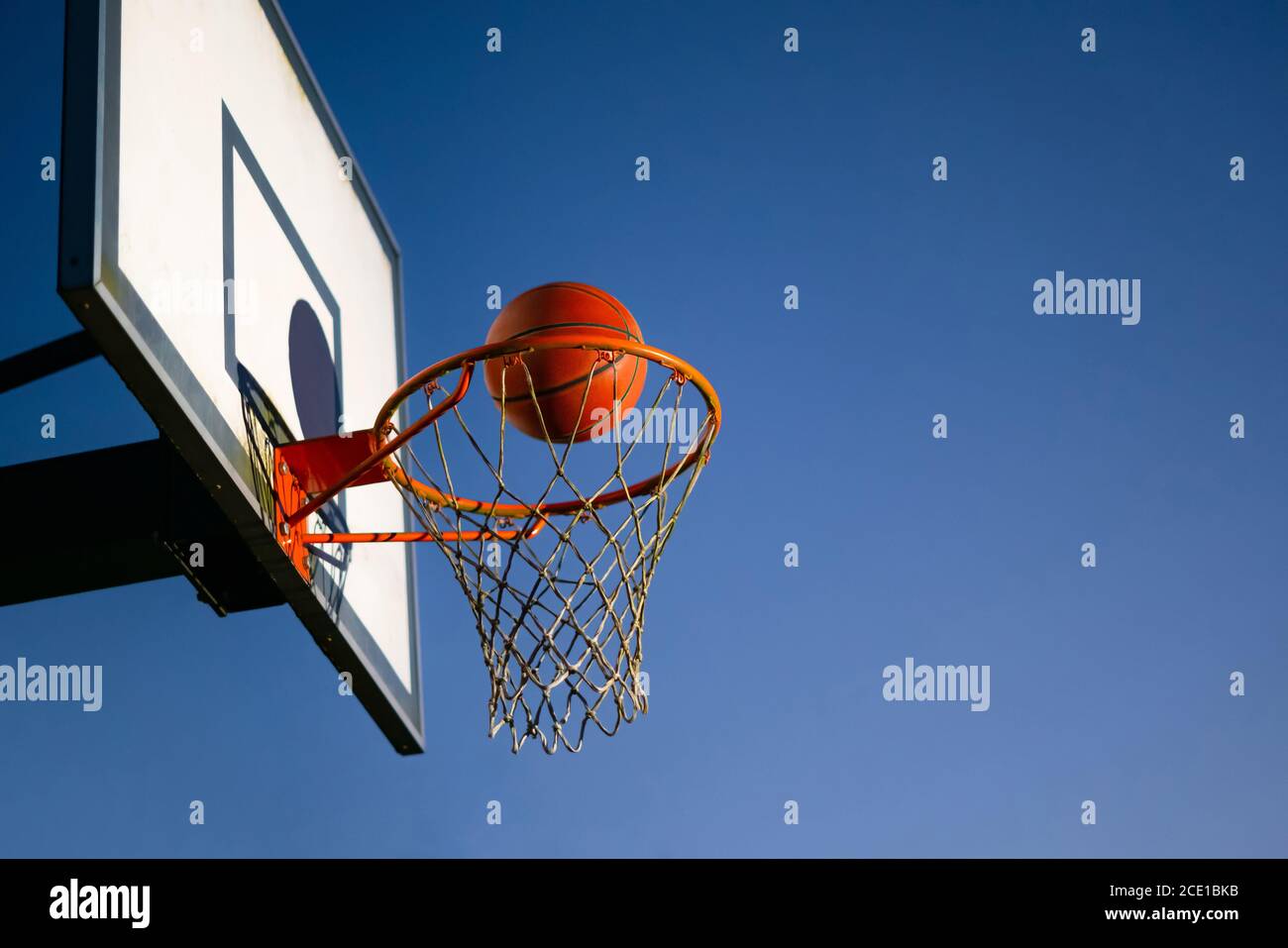 Street basketball ball falling into the hoop. Close up of orange ball