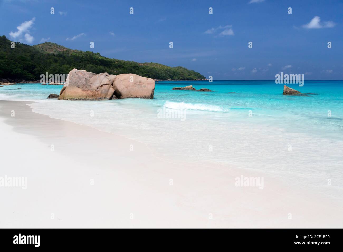 Beach with blue water and blue sky and some rocks Stock Photo - Alamy