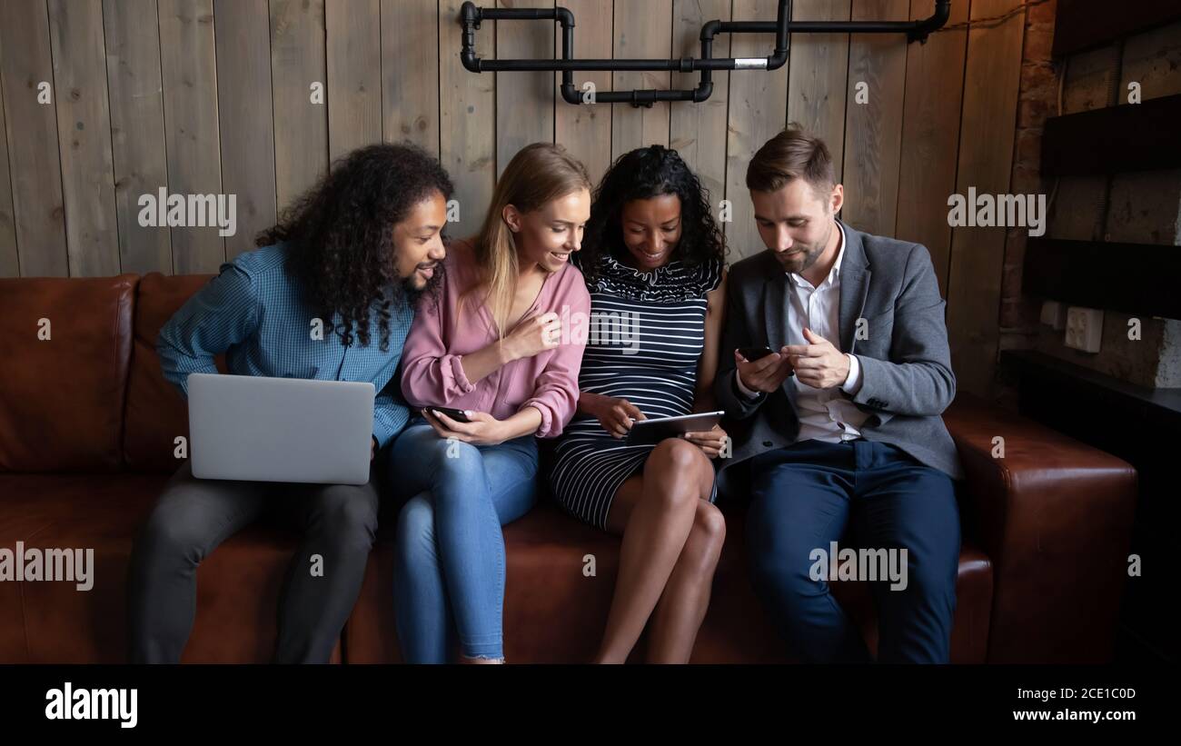 Happy diverse friends having fun together, looking at tablet screen Stock Photo