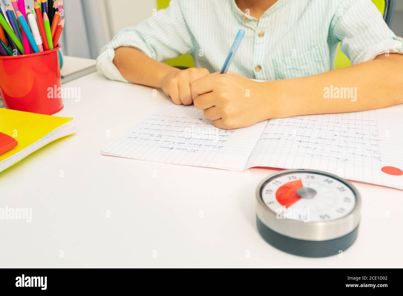 Little boy with lesson timer while doing writing exercise on background  Stock Photo - Alamy