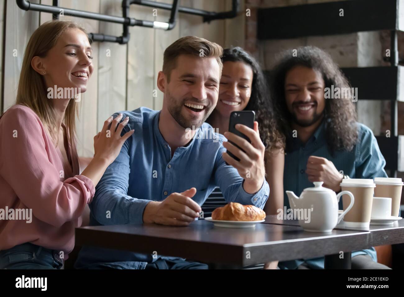 Overjoyed diverse people posing for photo in cafe together Stock Photo