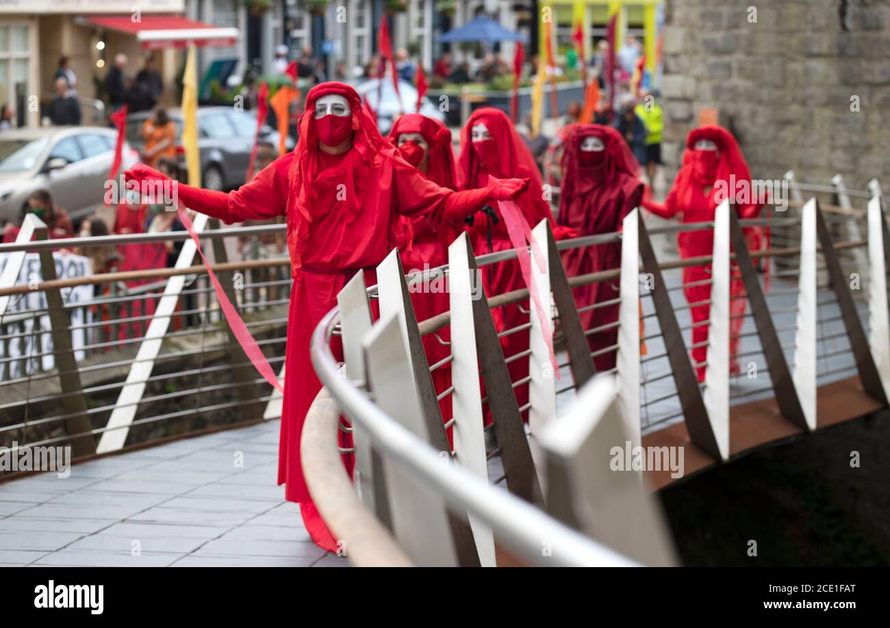 Caernarfon Castle, Wales, UK. 30 August 2020, Extinction Rebellion Protestors and Red Rebel Brigade take over Caernarfon Castle to protest about climate change and global warming. Children's shoes signify that it is the children that will suffer in the future. Red Rebels walk up to Caernarfon Castle Entrance Credit: Denise Laura Baker/Alamy Live News Stock Photo
