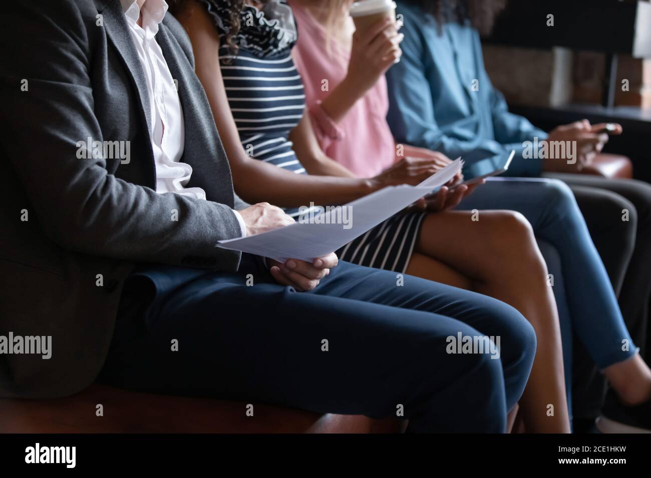 Close up diverse candidates sitting in row, using gadgets Stock Photo