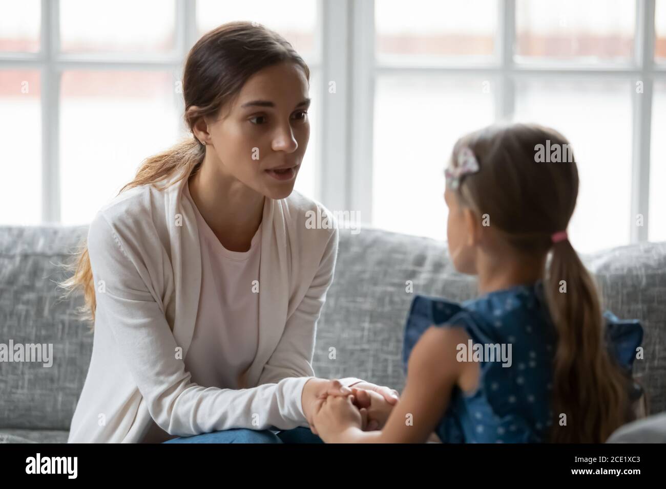 Worried young mommy supporting, giving advice to little daughter. Stock Photo