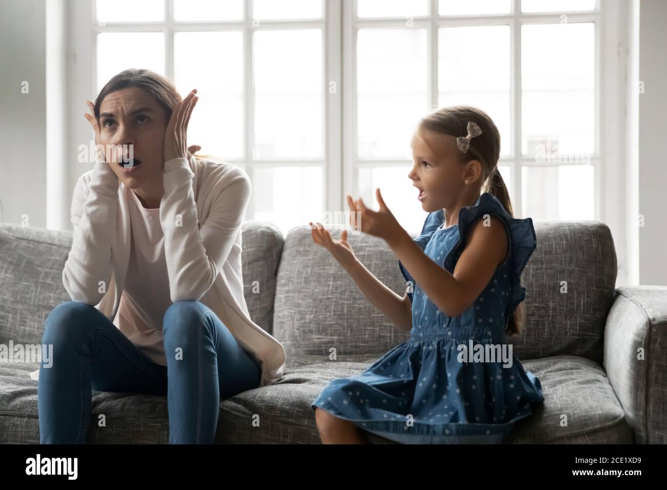 Stressed young woman covering ears ignoring naughty little child daughter. Stock Photo
