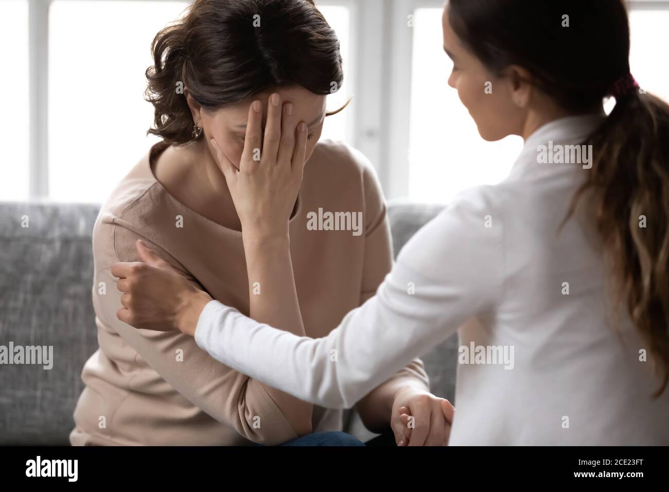Compassionate kind young woman supporting depressed unhappy older mother. Stock Photo