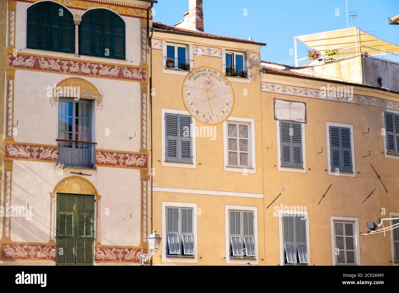 Old yellow buildings with sundial in the old town of Finalborgo, Finale Ligure, Liguria, Italy Stock Photo
