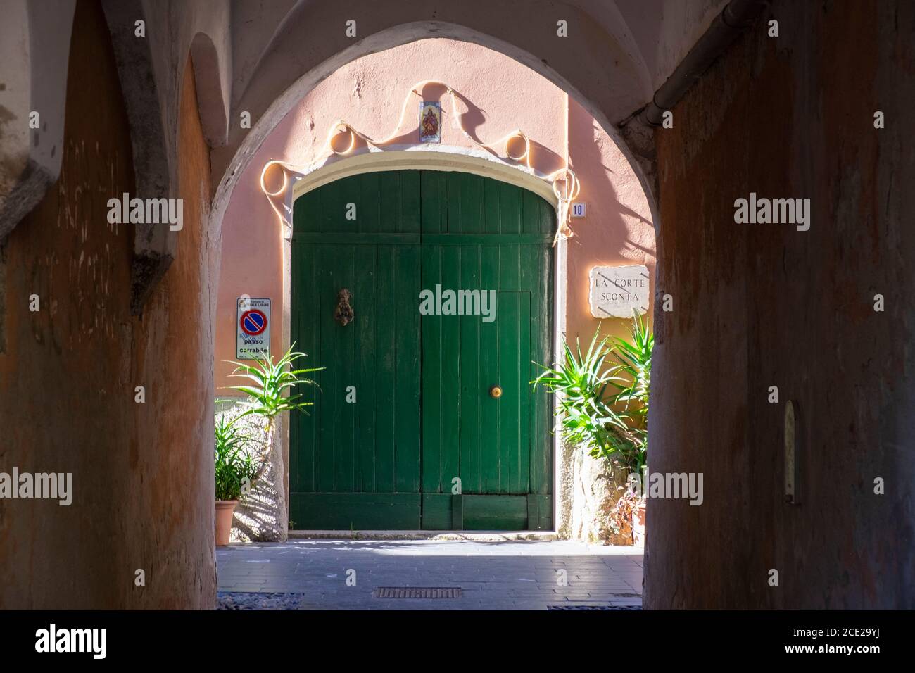 arch and green wooden old doorway in the old town of Finalborgo, Finale Ligure, Liguria, Italy Stock Photo