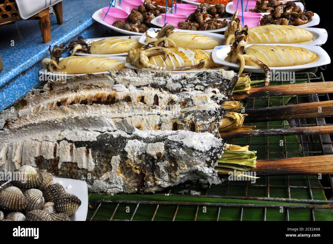 Close up of A spread of seafood on an outdoor grill displaying Thai delicacies of squid and more seafood at the Ayothaya Floating Market, in Thailand Stock Photo