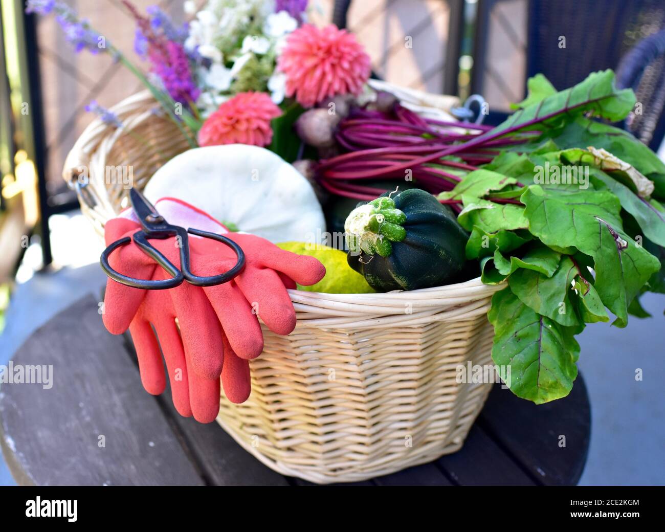 Freshly harvested organic home grown vegetables with beautiful cut flowers for cooking healthy meal and pretty table setting Stock Photo