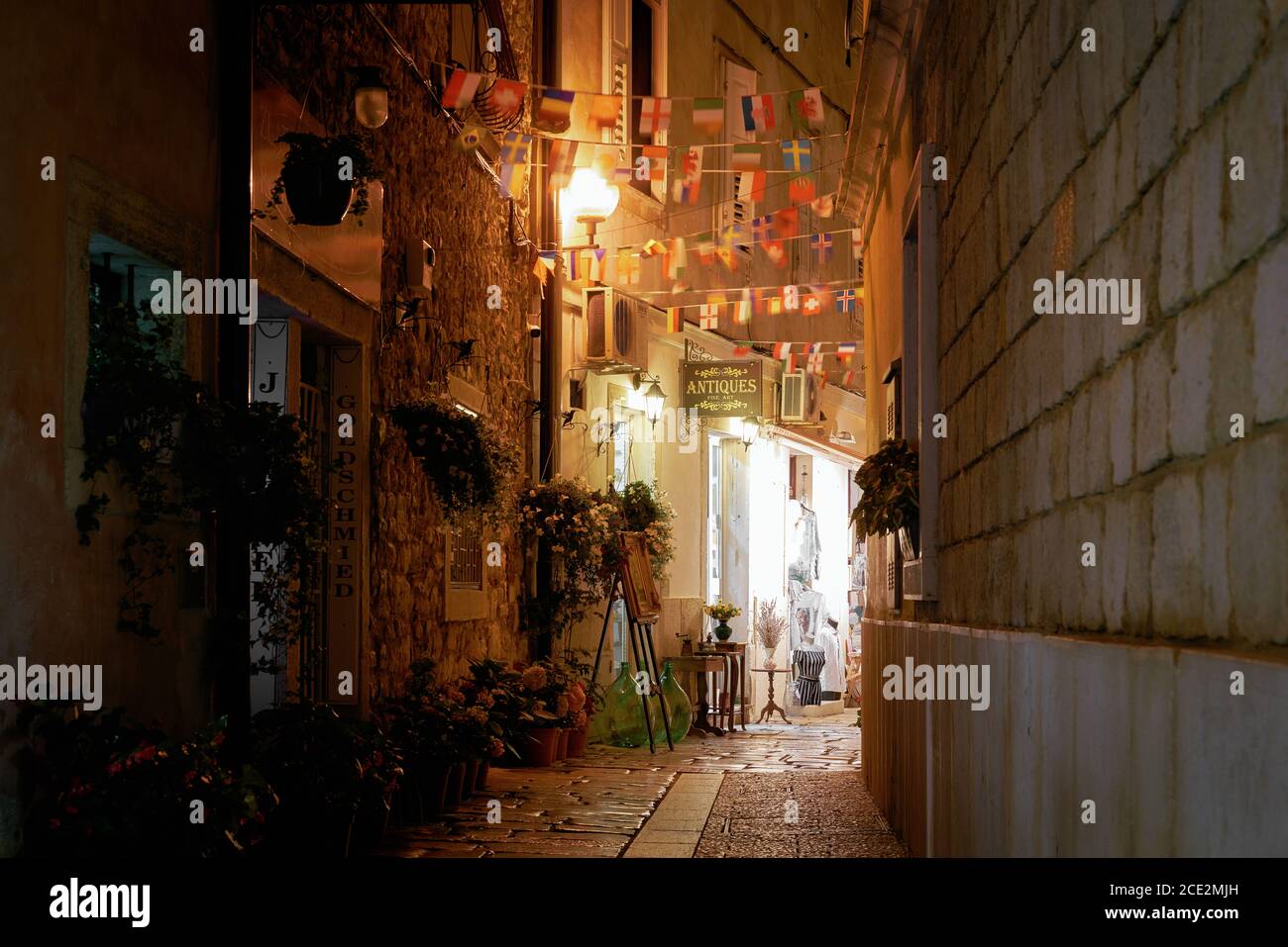 Shops in a narrow alley in the port city of Porec in Croatia in the evening Stock Photo
