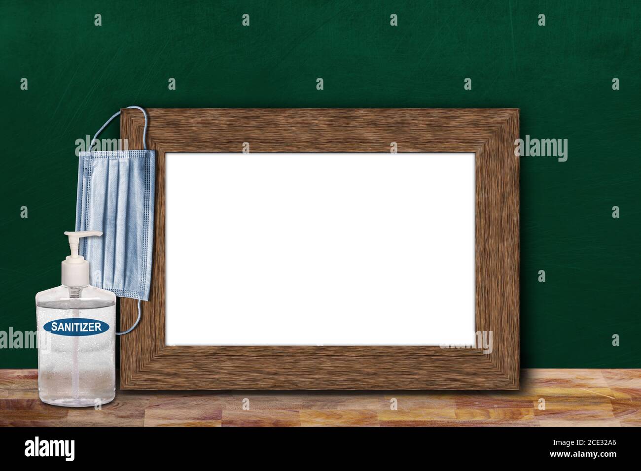 COVID-19 new normal education back to school concept in the classroom setting showing picture frame on chalkboard with copy space and face mask, hand Stock Photo