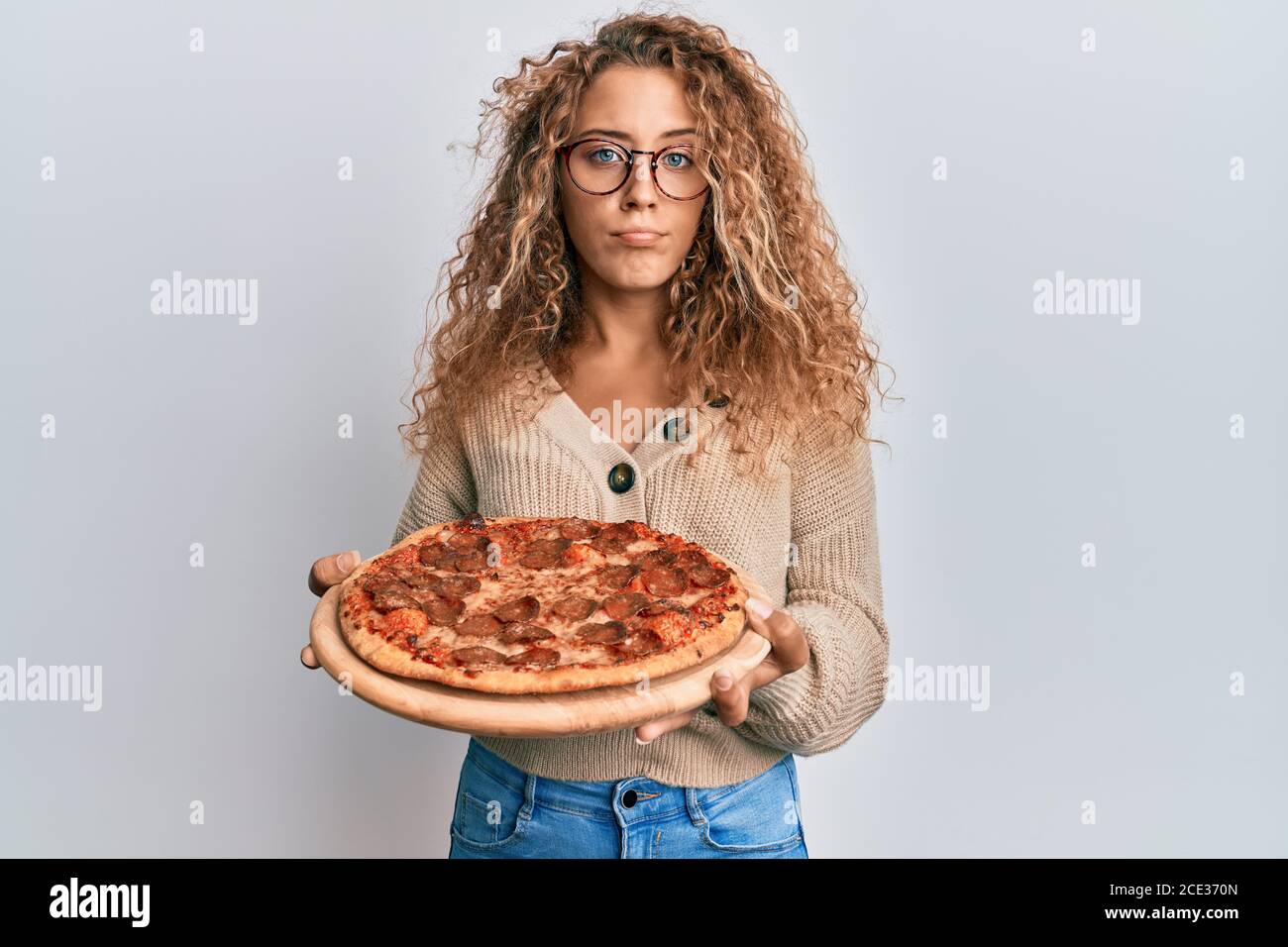 Beautiful caucasian teenager girl eating tasty pepperoni pizza